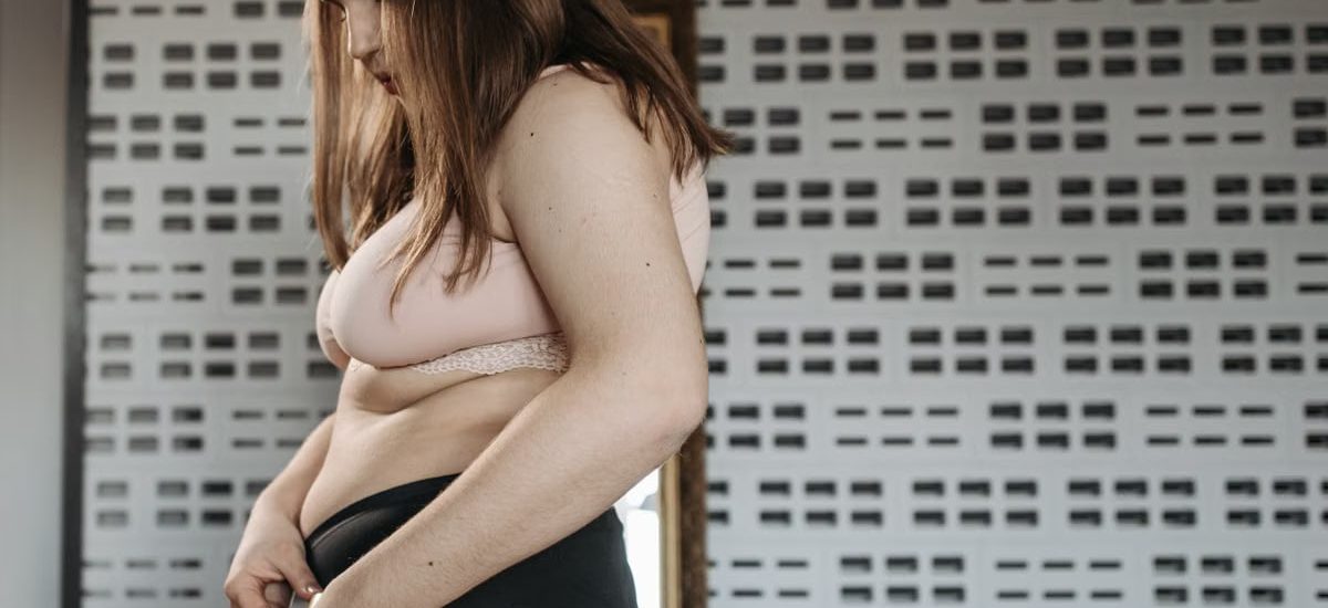 Confident young woman measures her hips in a stylish interior, embracing body positivity.